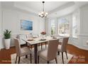 Elegant dining room with a bay window, hardwood floors, wainscoting, and a stylish chandelier at 1528 Ridge Haven Rd, Waxhaw, NC 28173