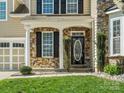 Close-up of the front entrance showcasing the stone facade, black door with oval window, and manicured landscaping at 1528 Ridge Haven Rd, Waxhaw, NC 28173