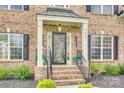 Inviting covered front porch with brick steps, black railing, and attractive landscaping at 1813 Robbins Meadows Dr, Waxhaw, NC 28173
