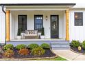 Inviting front porch with bench seating and gray painted stairs and lovely landscaping at 211 Killian Rd, Stanley, NC 28164