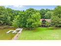 Lakefront home featuring a private dock, lush greenery, and well-maintained lawn at 307 Stillwater Rd, Troutman, NC 28166