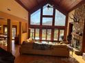 Inviting living room with vaulted ceilings, stone fireplace, and floor-to-ceiling windows overlooking lake at 307 Stillwater Rd, Troutman, NC 28166