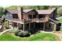 The exterior elevation of a multi-level stone home featuring a large porch overlooking manicured gardens at 7424 Windy Pine Cir, Denver, NC 28037