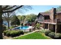 A beautiful backyard pool, with lush landscaping and a multi-level stone and wood home at 7424 Windy Pine Cir, Denver, NC 28037