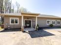 A beige home featuring a covered entrance with pillars and a solid black door with white trim windows at 7545 Brancy St, Kannapolis, NC 28081