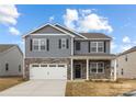 Charming two-story home with gray siding, stone accents, covered porch and two car garage at 7730 Woolsey Dr, Gastonia, NC 28056