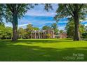 Expansive green lawn with stately brick home, featuring a covered walkway connecting to a guest house at 1035 Pee Dee Ave, Albemarle, NC 28001