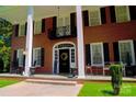 Inviting front porch with black shutters, white pillars, and a 