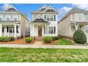 Inviting two-story home boasts a covered porch and meticulously maintained landscaping on a sunny day at 13712 Bonnerby Ct, Huntersville, NC 28078