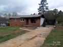 Exterior view of a single-story brick home showcasing its front yard and cracked driveway at 1842 Quail Run Dr, Kingstown, NC 28150