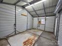 Inside the storage building in the carport, you can see a concrete floor and metal siding walls at 2021 Hilton Way Rd, Lancaster, SC 29720