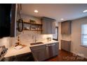 Well-lit kitchen boasts stainless appliances, grey cabinets, floating shelves, and a sleek countertop, complemented by hardwood flooring at 4609 Hedgemore Dr # I, Charlotte, NC 28209