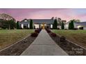 Charming single-story home featuring a well-manicured lawn and inviting yellow front door at twilight at 4808 Truscott Rd, Charlotte, NC 28226