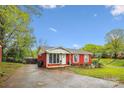 Quaint red brick home featuring a well-kept lawn and inviting front entrance at 6800 Deanwood Pl, Charlotte, NC 28217