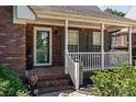 Inviting front porch with brick steps, white railings, and a beautifully patterned outdoor rug at 1008 Autumn Ln, Concord, NC 28025
