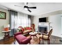 Bright living room with fireplace, large windows with sheer curtains, and a ceiling fan at 1110 S New Hope Rd, Gastonia, NC 28054