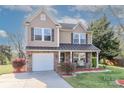 Two-story home featuring stone accents, covered porch, manicured lawn and mature trees at 1135 Valley St, Statesville, NC 28677