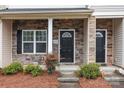Inviting front entrance featuring a stone facade, black door with transom window, and manicured shrubs at 12550 Mcgrath Dr, Charlotte, NC 28269