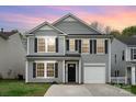 Charming two-story home with gray siding, black shutters, a well-kept lawn, and attached garage at sunset at 2005 Dunsmore Ln, Waxhaw, NC 28173