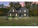 Two-story home with brick and siding, black shutters, and a well-manicured lawn at dusk at 3018 Corinth Church Rd, Monroe, NC 28112