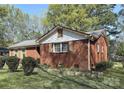 A cozy brick home featuring a well-maintained yard, side garden, and a classic design with mature trees at 3220 Wiseman Dr, Charlotte, NC 28227