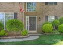 Close up of a classic brick home entrance with manicured shrubs and stylish front door at 3712 Autumn Gold Ct, Charlotte, NC 28278