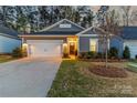 Inviting home exterior with a well-manicured lawn, illuminated entryway, and attached two-car garage at 4427 Bright Rd, Charlotte, NC 28214