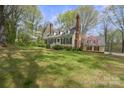 Wide view of two-story yellow home with blue shutters, brick chimney and landscaped front yard at 469 Augusta Dr, Statesville, NC 28625
