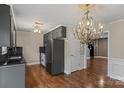 Bright dining area with dark cabinets, wood floors, wainscoting, elegant chandelier, and door to adjoining room at 485 Camrose Ne Cir, Concord, NC 28025