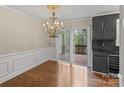 Bright dining room with hardwood floors, elegant chandelier, wainscoting, dark cabinets, and sliding door to deck at 485 Camrose Ne Cir, Concord, NC 28025