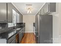 Well-lit kitchen featuring dark granite countertops, wooden floors, black backsplash, and stainless steel appliances at 485 Camrose Ne Cir, Concord, NC 28025