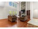 Bright, open living room featuring a stone fireplace, large windows, hardwood floors, and built-in shelving at 7798 Sand Trap Ln, Stanley, NC 28164