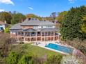 Expansive two-story back porch overlooking a swimming pool, surrounded by lush greenery and mature trees at 7980 Bradford Ln, Denver, NC 28037