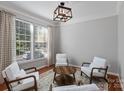 Cozy living room featuring hardwood floors, neutral walls, and four comfortable white armchairs around a coffee table at 8311 Camberly Rd, Huntersville, NC 28078