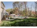 A backyard featuring an in-ground pool, surrounded by a stone patio, lush greenery and mature trees at 8718 Canter Post Dr, Charlotte, NC 28216