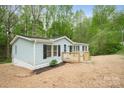 Charming home featuring a light blue exterior, a wooden deck, and black shutters against a backdrop of lush trees at 102 Lansdale Ave, Lincolnton, NC 28092
