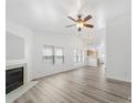 Bright living room featuring a fireplace, ceiling fan, and neutral color palette, with views of kitchen at 10441 Hugue Way, Charlotte, NC 28214