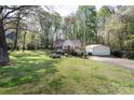 Large grassy yard featuring mature trees and an outbuilding/garage at 11100 Pine Grove Ave, Mint Hill, NC 28227