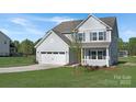 Charming two-story home featuring a welcoming front porch, attached two-car garage, and freshly landscaped yard at 12437 Walker Dr # 89, Stanfield, NC 28163