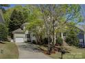 Exterior showcasing a tan two-story home, attached garage, and a long driveway at 14103 Grand Traverse Dr, Charlotte, NC 28278