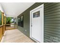 Inviting covered porch featuring wood decking, white trim, and a stylish front door with glass accents at 1451 Cherryville Rd, Shelby, NC 28150