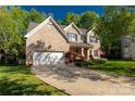 Attractive brick home featuring a two-car garage, lush landscaping, and a welcoming front porch at 206 Coburn Ct, Fort Mill, SC 29715
