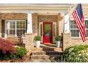 Inviting front porch featuring a red door, white columns, potted plants, and an American flag at 206 Coburn Ct, Fort Mill, SC 29715