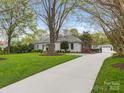 Long driveway leads to a white brick home with manicured landscaping, lawn and a detached garage at 2219 Richardson Dr, Charlotte, NC 28211