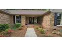 Inviting brick home entrance featuring well-kept landscaping and an oval-window front door at 413 Parallel Dr, Harrisburg, NC 28075