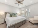 A bedroom with neutral tones, ceiling fan, plush carpet and a large window with wood blinds at 4141 Polluck Way, Charlotte, NC 28209