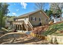 Charming home exterior with a wooden deck, stone foundation, and landscaped yard at 458 Pinehaven Dr, Badin Lake, NC 28127