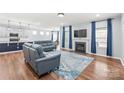 Open-concept living room featuring hardwood floors, blue sofas, fireplace, and modern decor at 7662 Tanglewood Way, Denver, NC 28037