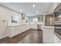 Bright kitchen showcasing stainless appliances, white cabinetry, and stunning hardwood floors at 8308 Knights Bridge Rd, Charlotte, NC 28210