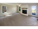 Living room featuring a painted brick fireplace, neutral walls, carpet flooring, and exterior access at 1090 Briarcliff Rd, Mooresville, NC 28115